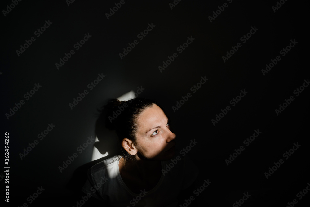 Girl sitting alone in sunlight pocket in dark room. mental health concept Girl sitting alone in sunlight pocket in dark room. mental health concept