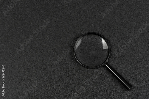 Black magnifying glass on black background. Magnifier. Search