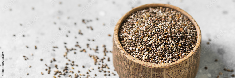Chia seeds in a wooden bowl on the light gray kitchen table. Chia seeds for a healthy diet. Superfood Chia close-up. Banner with space for text Chia seeds in a wooden bowl on the light gray kitchen table. Chia seeds for a healthy diet. Superfood Chia close-up. Banner with space for text
