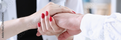 Friendly female doctor hold male patient hand in office during reception. Examination result  positive test  calm down  promise and cheer up  grief and suffer  treatment  condolence  ethics concept