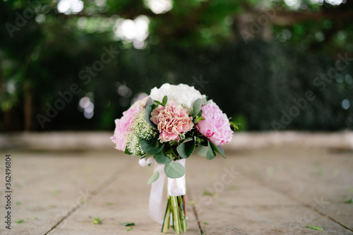 bridal bouquet of pink and white peonies, branches of eucalyptus tree, ammi and white ribbons outdoor © Nadtochiy