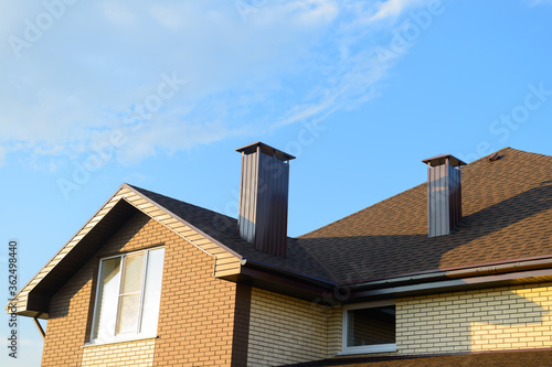 The roof of the house is made of sheets of brown metal tiles with a pipe