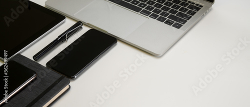 Modern office desk with digital devices, pen, schedule book and copy space on white table