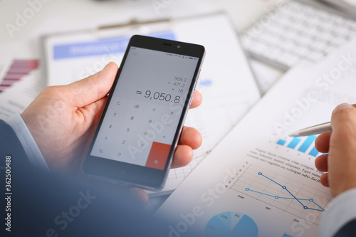 Smartphone calculator and financial statistics ondisplay tablet at office table closeup. Internal Revenue Service inspector sum check, irs investigation, earnings, savings, loan and credit concept