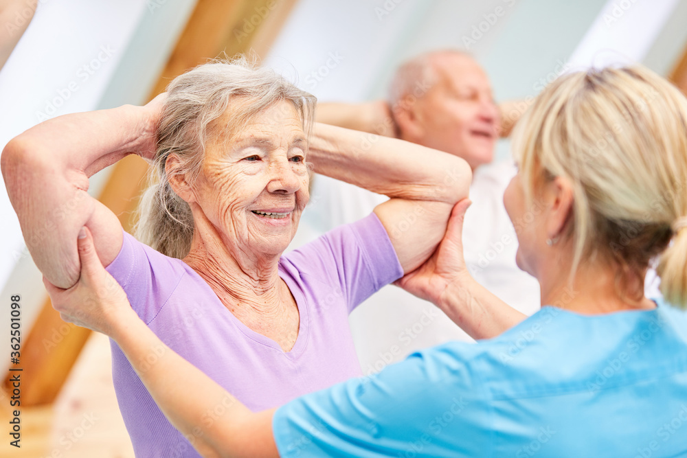 Trainer hilft Seniorin beim Rückentraining Trainer hilft Seniorin beim Rückentraining