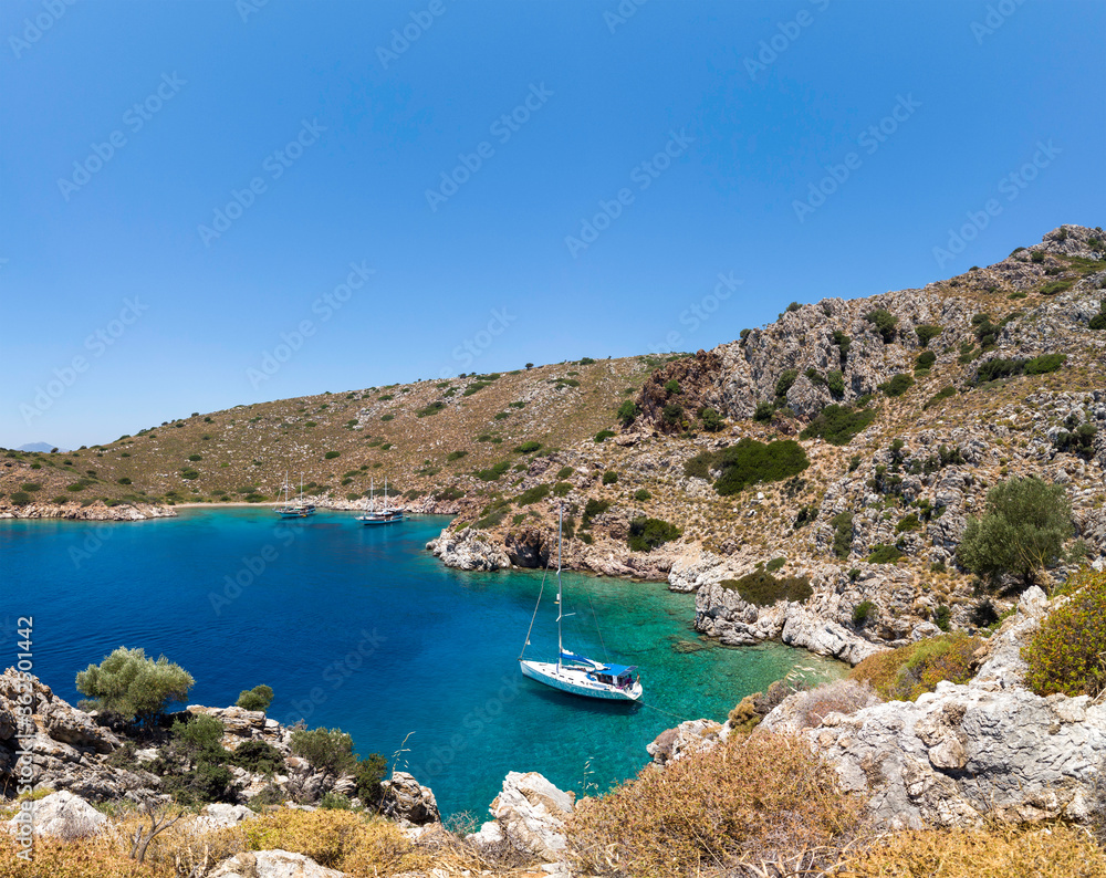Sailing boat anchored in a beautiful turquoise color water bay in aegean sea.