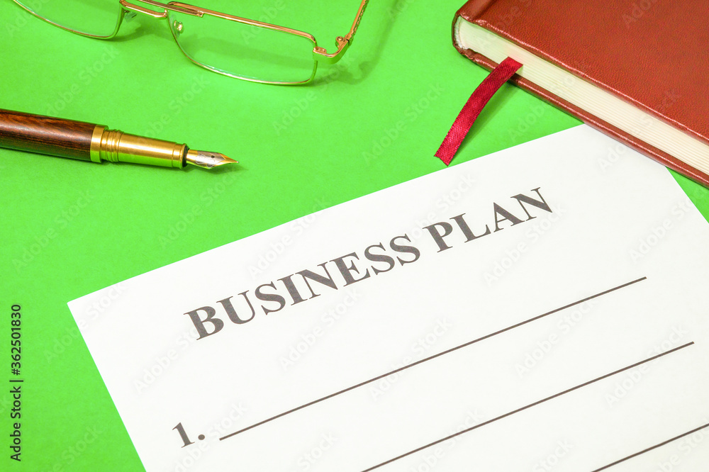 Blank of business plan and notepad on a green office desk Blank of business plan and notepad on a green office desk