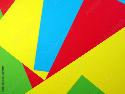pile of colorful paper sheet (green, red, yellow, blue), colored paper stacked into geometric shape for abstract background, flat lay close up top view