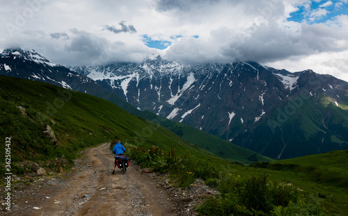 Svanetia, Georgia: Cyclist rides a path with mountains in the background on a cloudy and stormy day