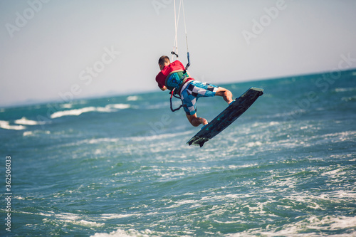 Professional kiter makes the difficult trick on a beautiful background. Kitesurfing Kiteboarding action photos man among waves quickly goes