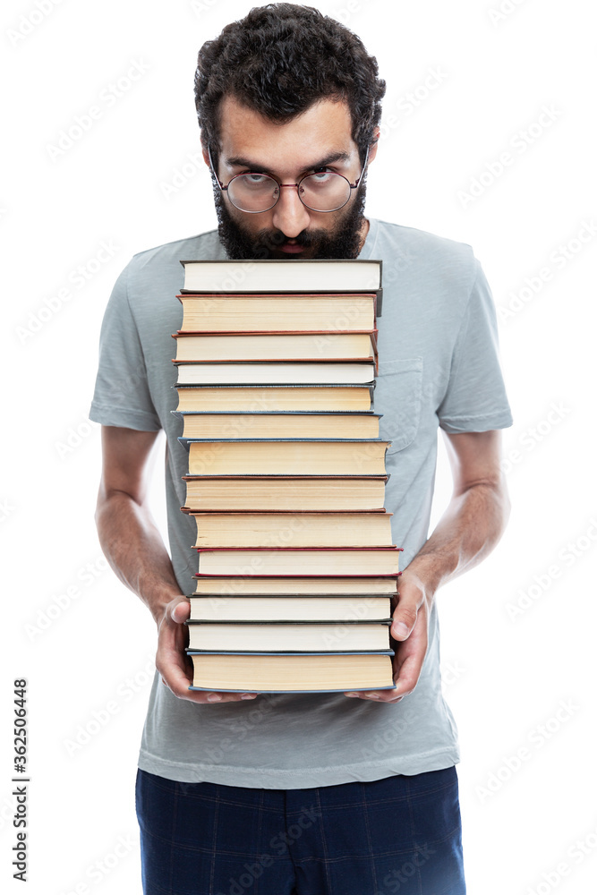 A young man with glasses and a beard holds in his hands a large stack of books. Education and training. Isolated on a white background. Vertical. A young man with glasses and a beard holds in his hands a large stack of books. Education and training. Isolated on a white background. Vertical.