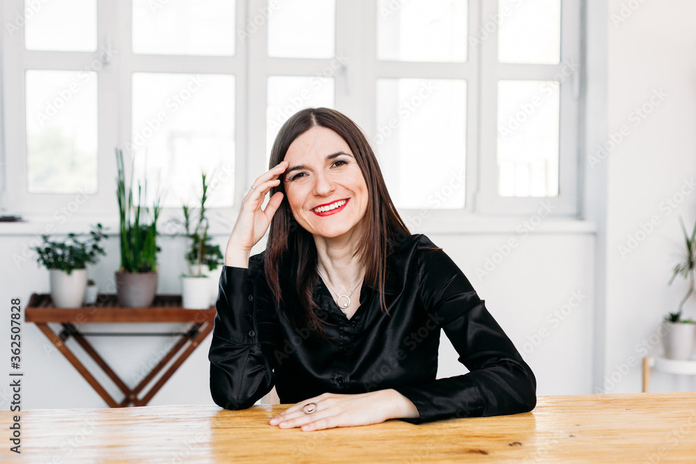 Girl sitting at the table, dark clothes, house, plants and smile, youth, beauty Girl sitting at the table, dark clothes, house, plants and smile, youth, beauty