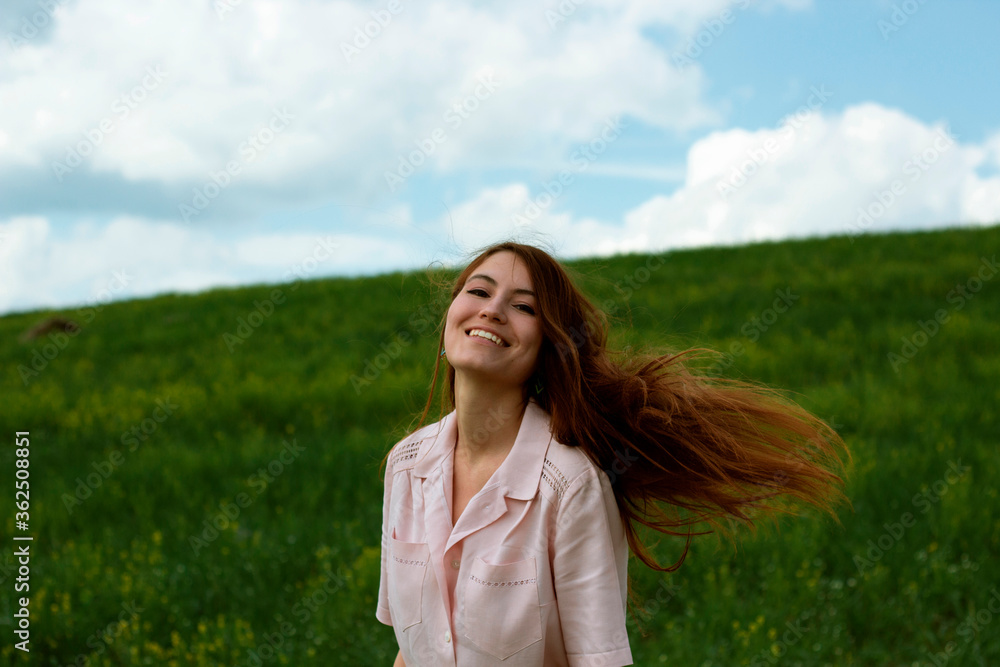 Happy girl with flying hair on the field. Portrait of a smiling girl against a green field. Happy girl with flying hair on the field. Portrait of a smiling girl against a green field.