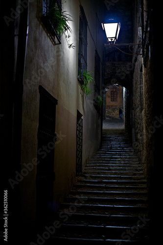 Alley with a staircase going up illuminated by a slight light from a lamppost