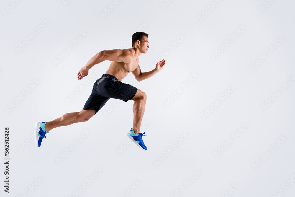 Full body profile photo of handsome sportsman dark skin guy naked chest jump high up running fast sprint workout exercise fat burn wear shorts sneakers isolated white color background