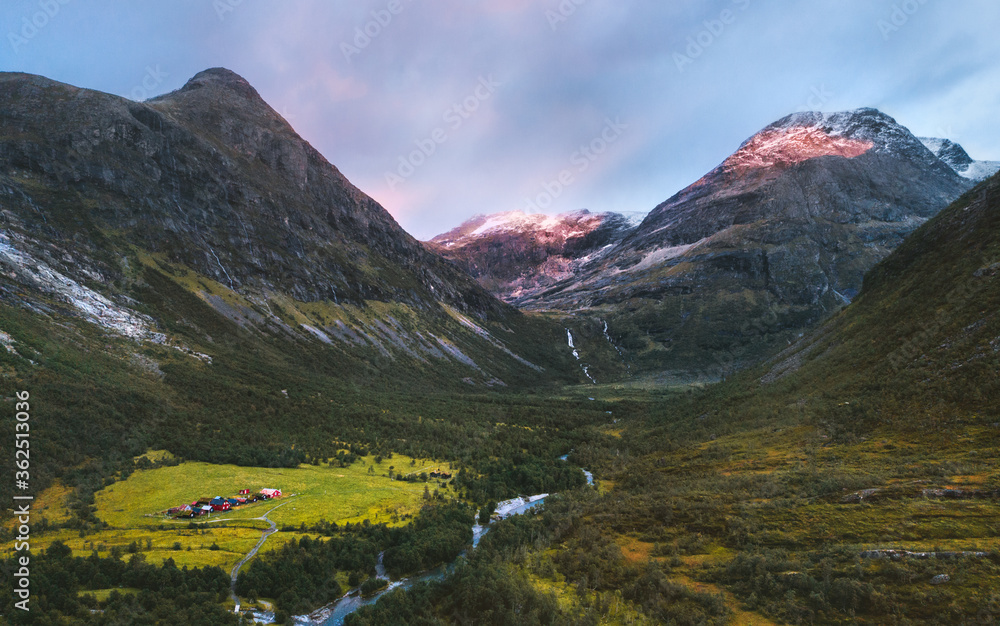 Fototapeta premium Aerial view sunset mountains valley and farm houses in Norway landscape travel beautiful destinations Jostedalsbreen national park.