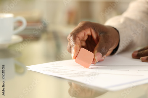 Black man hands erasing with rubber at home
