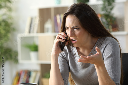 Angry woman calling arguing on phone at home photo