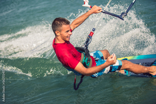 Professional kiter makes the difficult trick on a river. Kitesurfing Kiteboarding action photos man among waves quickly goes