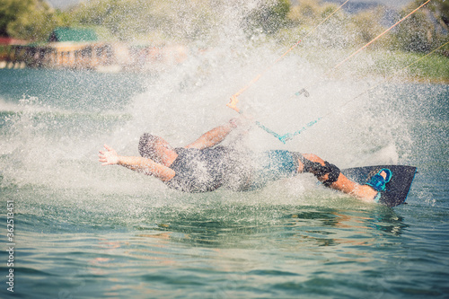 Professional kiter makes the difficult trick on a river. Kitesurfing Kiteboarding action photos man among waves quickly goes