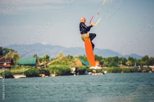 Professional kiter makes the difficult trick on a river. Kitesurfing Kiteboarding action photos man among waves quickly goes