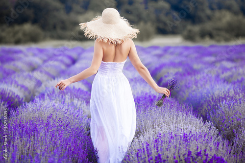Unrecognizable young woman standing on lavender field. Lady in summertime