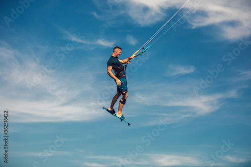 Professional kiter makes the difficult trick on a beautiful background. Kitesurfing Kiteboarding action photos man among waves quickly goes