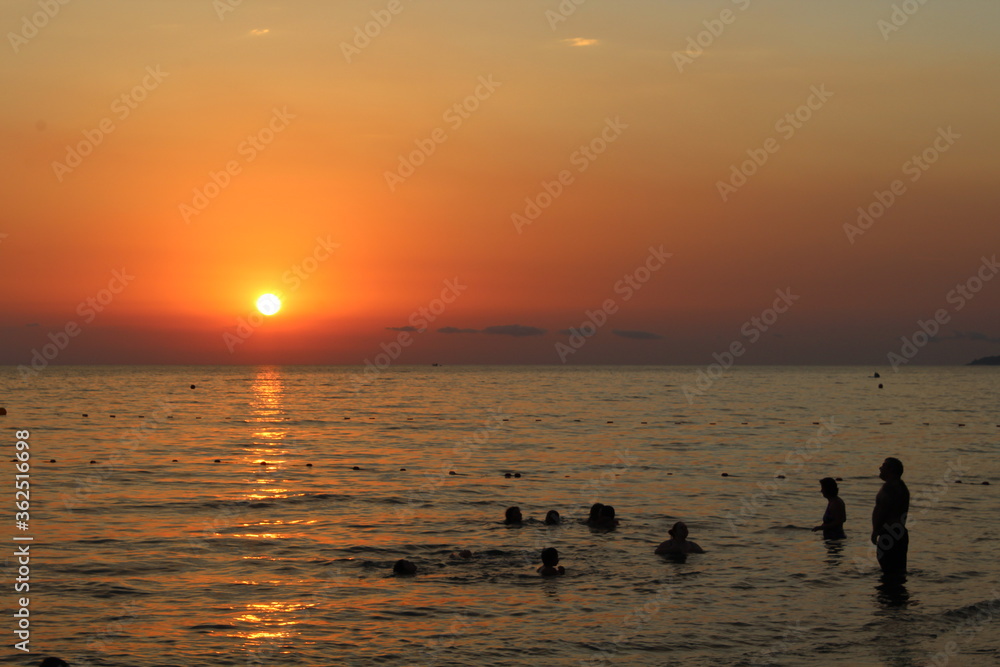 People's silhouette in the sea in sunset