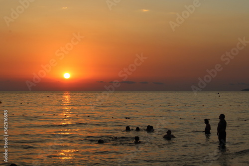 People's silhouette in the sea in sunset © Elena