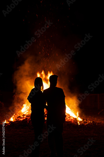 Silhouette of a couple in front of a giant bonfire