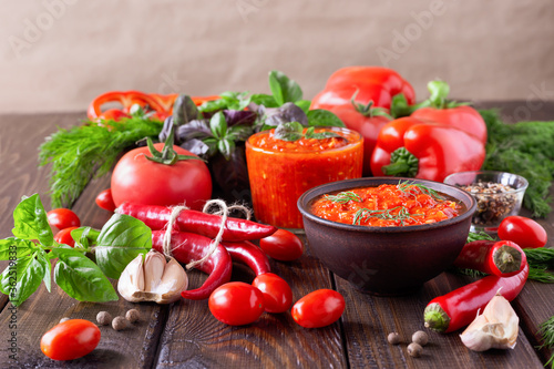 Balkan sauce ajvar and ingredients for its preparation on a wooden table. Serbian traditional food