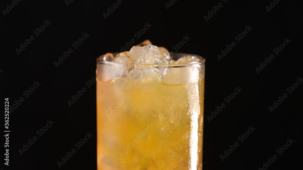 Sex on the beach cocktail in highball glass with water drops rotates on black background. Close up, shallow depth of the field. Sex on the beach cocktail in highball glass with water drops rotates on black background. Close up, shallow depth of the field.