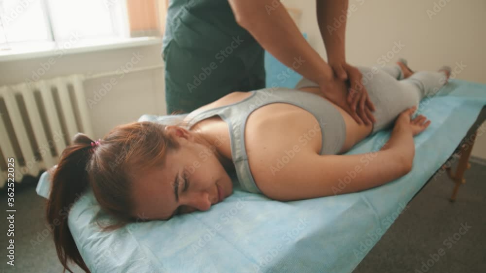 Osteopath treatment - the doctor pushing on the loin of young woman with his palms and elbows