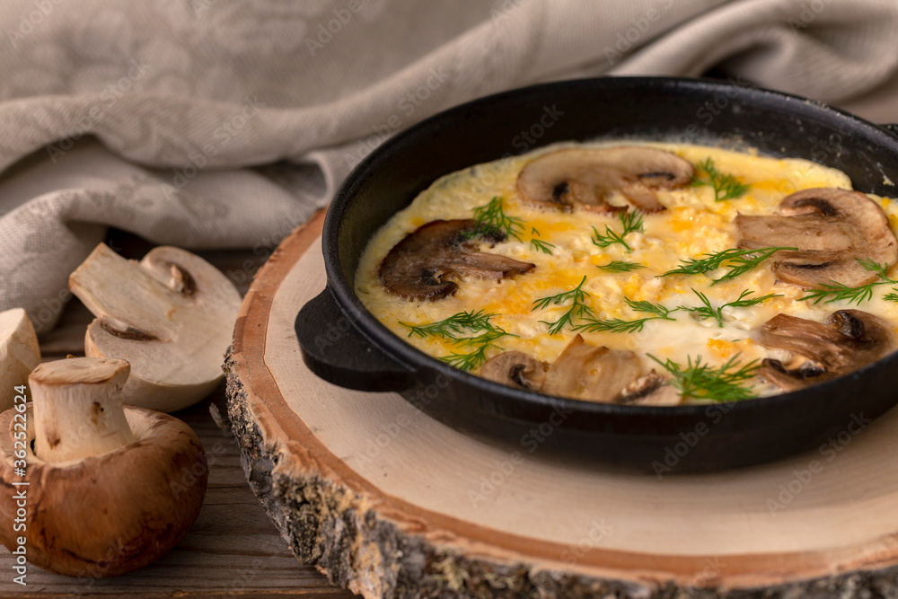 Omelet with mushrooms in a cast-iron pan. Champignon mushrooms. Home kitchen. Healthy eating