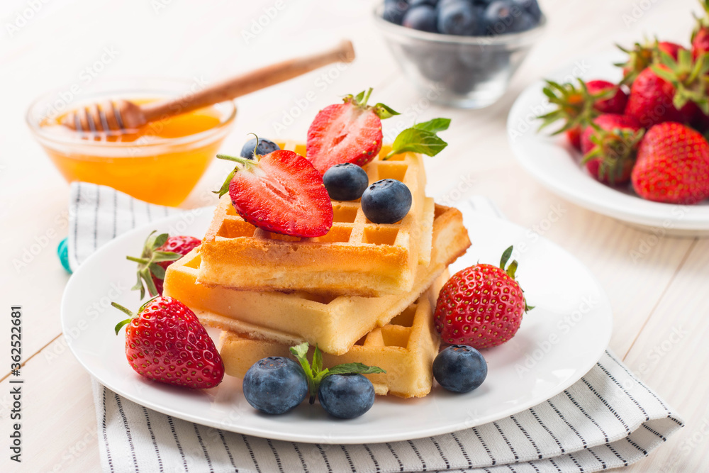 Fresh homemade food of berry Belgian waffles with honey, chocolate, strawberry, blueberry, maple syrup and cream. Healthy dessert breakfast concept with juice Fresh homemade food of berry Belgian waffles with honey, chocolate, strawberry, blueberry, maple syrup and cream. Healthy dessert breakfast concept with juice