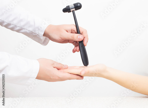 A neurologist examines a girl s palm chin reflex with a neurological hammer. Cervicocranialgia and oral automatism