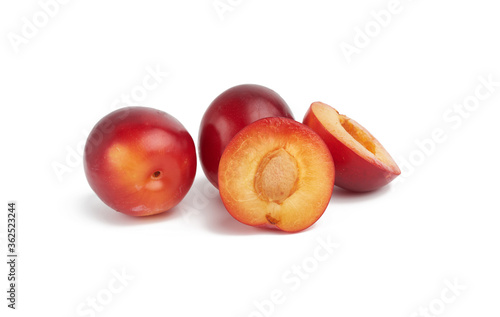 ripe red whole and halves of plum isolated on white background