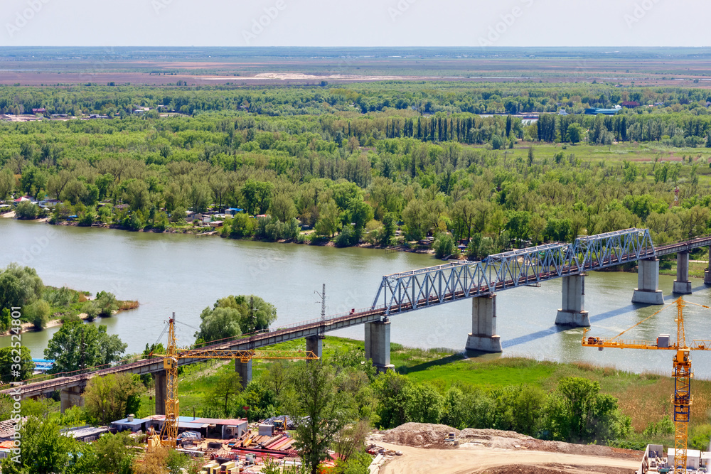 Fototapeta premium The railroad bridge over river among green forest. Don river, Green Island, Rostov-on-Don, Russia