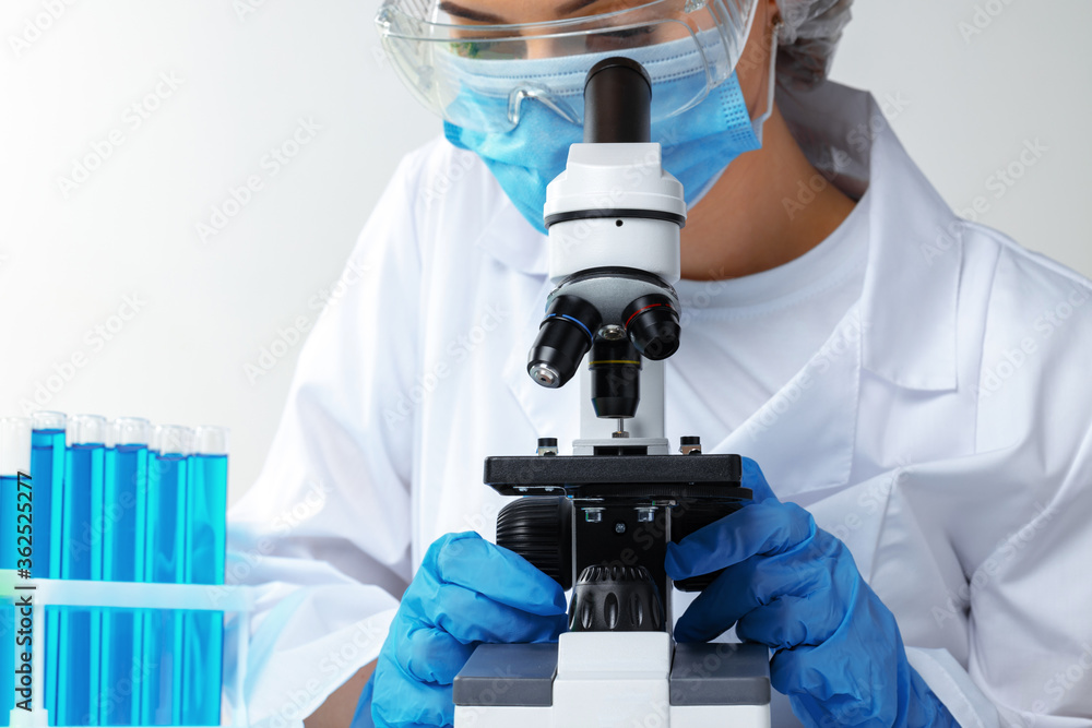 Woman scientist looking through a microscope in laboratory Woman scientist looking through a microscope in laboratory