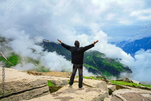 Hiker cheering elated and blissful with arms raised in the sky after hiking, Himachal Pradesh, India.