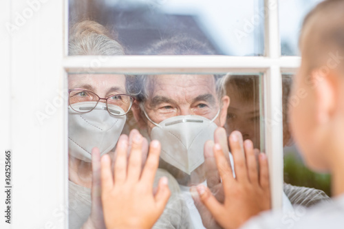Boy communicates with his grandparents through a window during the coronavirus epidemic