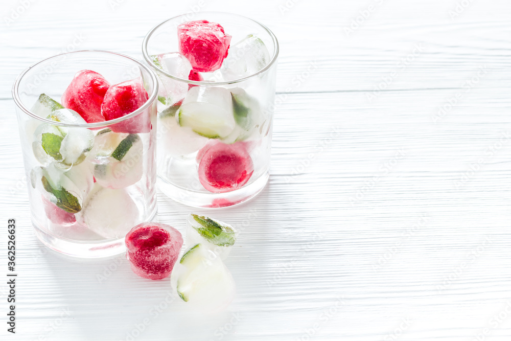 Cocktail glasses with berries in ice cubes on white table copy space Cocktail glasses with berries in ice cubes on white table copy space