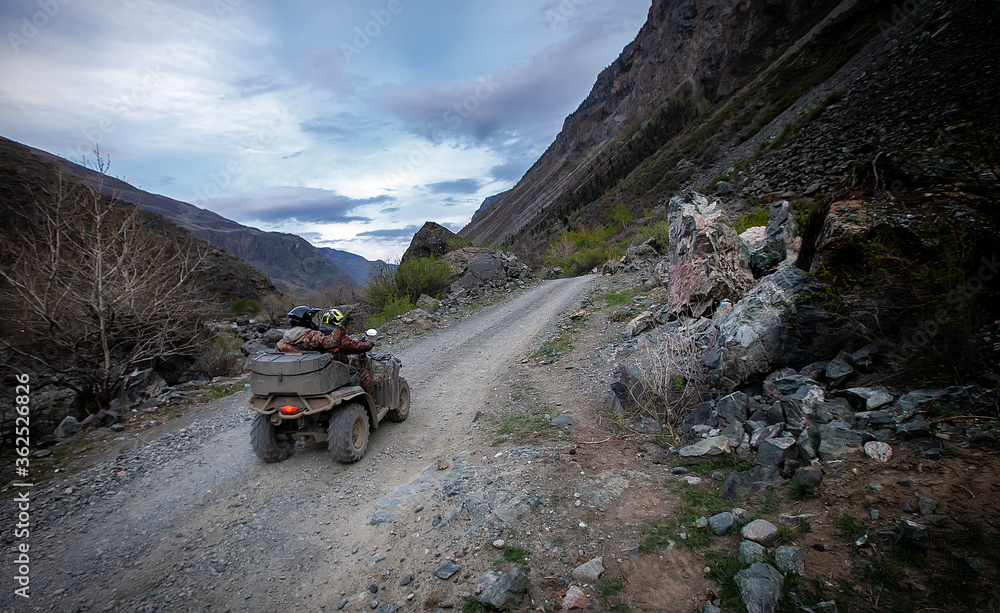 tourist ATV rides on a rocky road in a mountain gorge
