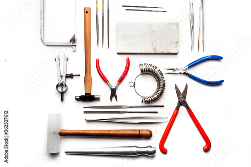 Different goldsmiths tools on the jewelry workplace. Desktop for craft jewelry making with professional tools. White background. 
