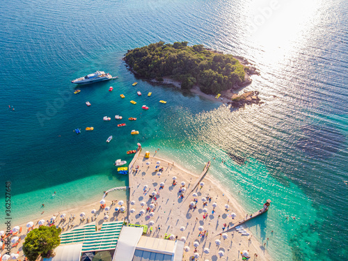 Aerial view of a beautiful white sand beach with turquoise water and relaxing people on a sunny day. Ksamil, Albania. photo