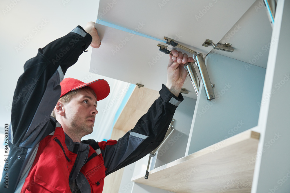 Furniture assembling. Professional worker installing wardrobe lifting ...