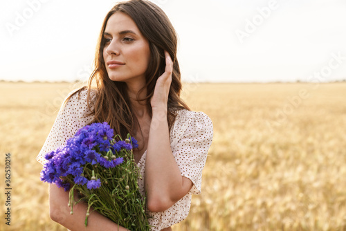 Photo of beautiful cute woman posing while walking on wheat field