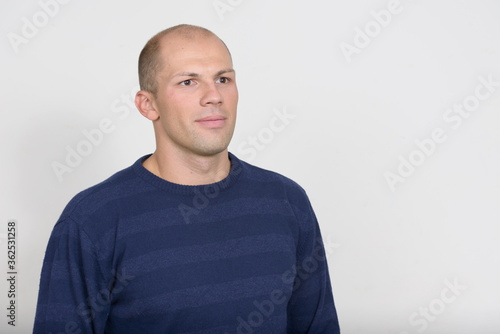 Portrait of young handsome bald man thinking