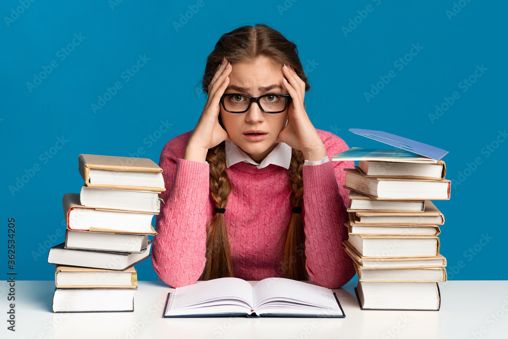 Exam preparation. Teen girl holding head among books Exam preparation. Teen girl holding head among books