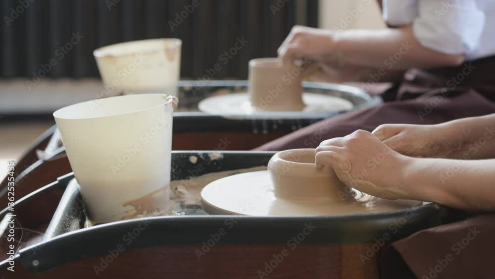 Two female ceramic artists in apron using clay material working in potter studio. Evening freelance distance learning. Adult hobby adventure. Winter educating leisure. Training in modern workshop. Two female ceramic artists in apron using clay material working in potter studio. Evening freelance distance learning. Adult hobby adventure. Winter educating leisure. Training in modern workshop.